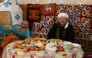 Kazakh in yurt with food for guests.